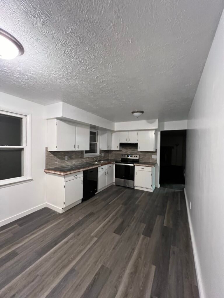 a kitchen with white cabinets and a wood floor