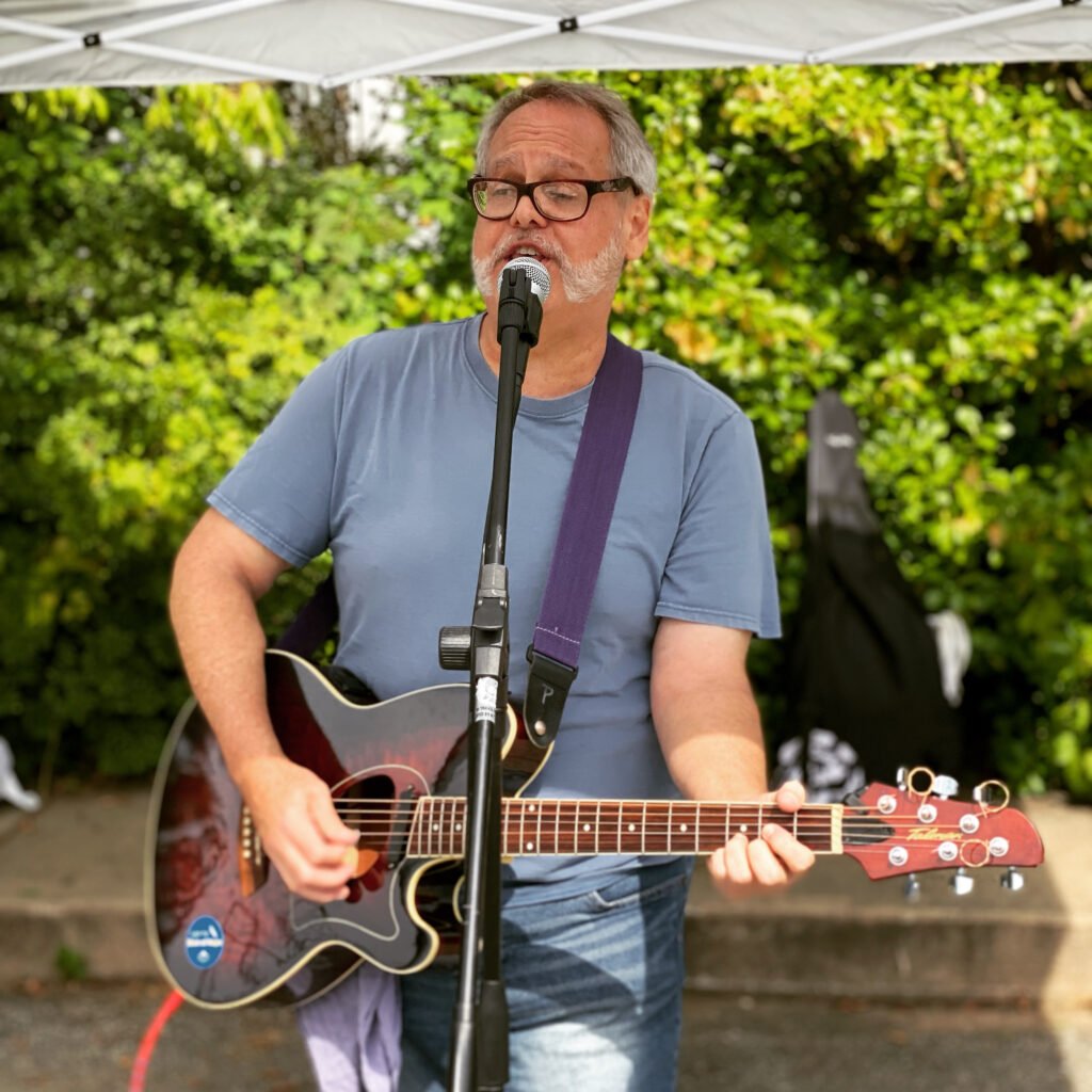 a man playing guitar and singing into a microphone